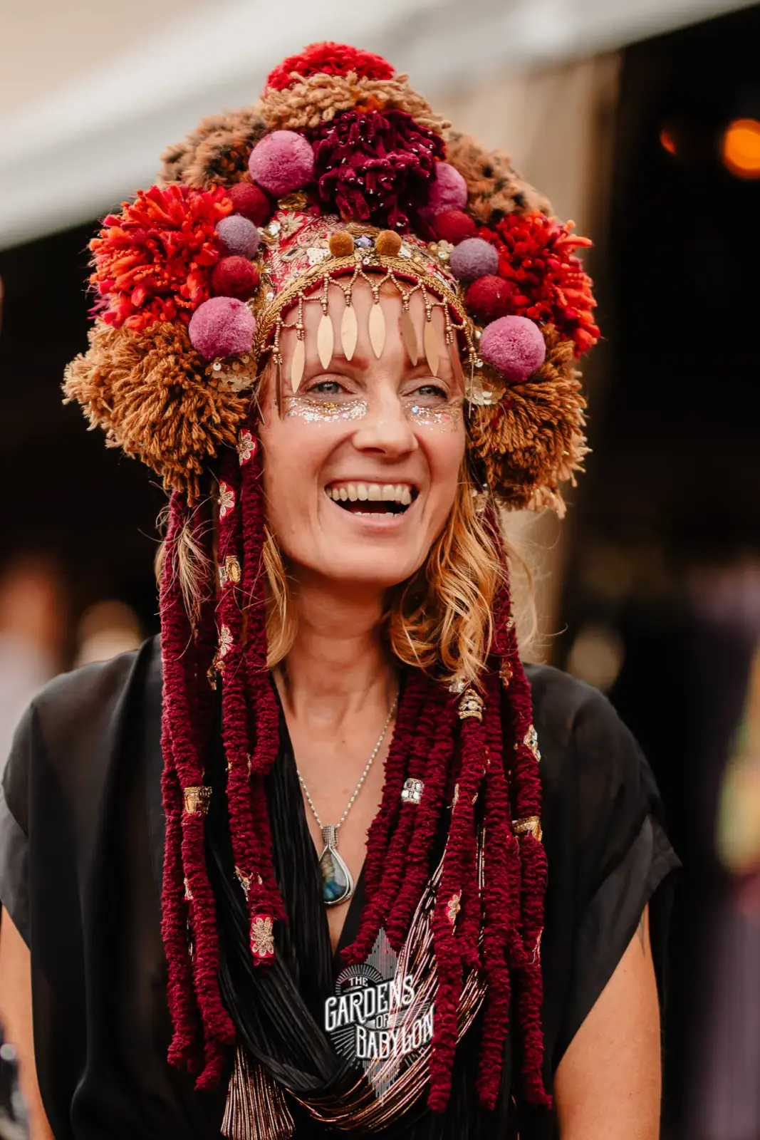 A member of the family laughing under a headdress of pom-poms and flowers